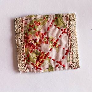 A hand quilted coaster, square shape, keeps cup hot or cold.